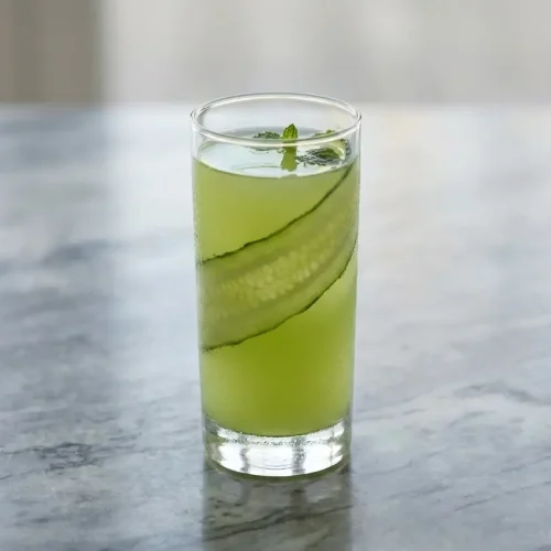 Jus detox concombre frais infusé au gingembre piquant et curcuma noir terreux dans un verre haut.