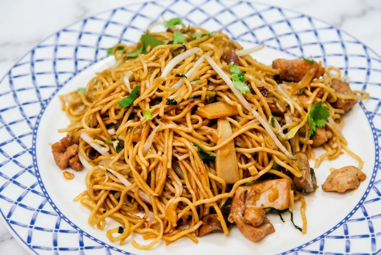 Wok fumant de la recette nouilles sautées au poulet avec une viande très tendre grâce au veloutage.